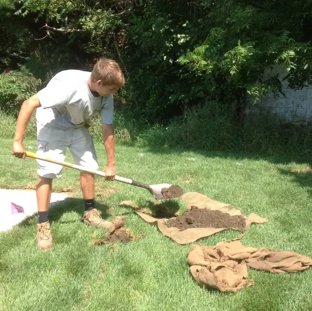 Fleming crew member with a shovel lifting sod beside burlap on a lawn